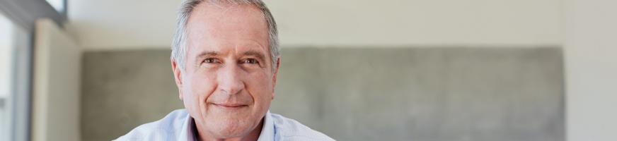 Homme cinquantenaire assis sur un canapé, souriant et serein