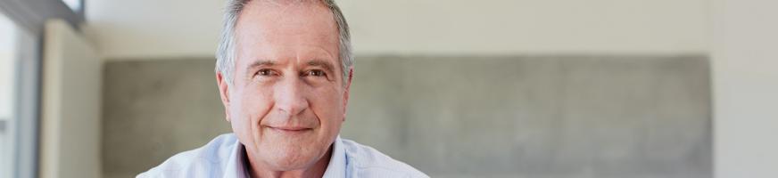 man in his fifties seated on a sofa, smiling and looking confident in the future